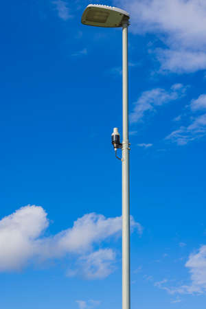 Close up view of light sensor on street lighting pole on blue sky with rare white clouds background. Sweden.の写真素材