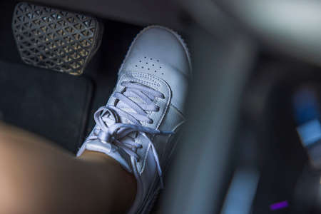 Close up view of female foot in white sneakers on electric vehicle gas pedal. Sweden.の写真素材