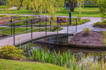Beautiful landscape view of old bridge over small pond in park on sunny summer day. Sweden.