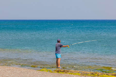 Beautiful view of fisherman catching fish on spinning rod in Mediterranean sea. Rhodes. Greece.の写真素材