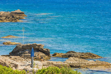 Beautiful landscape view of empty sun bed and sun umbrella on rocky sea cost.の写真素材