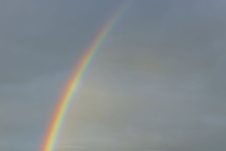Close up view of rainbow in cloudy evening summer sky. Sweden.