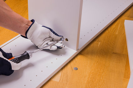 Close up view of man's hands assembling white furniture in an apartment.の写真素材