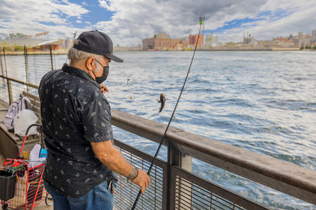 View of fisherman on Brooklyn Bridge catching small fish. New York, USA. 09.21.2022.のeditorial素材