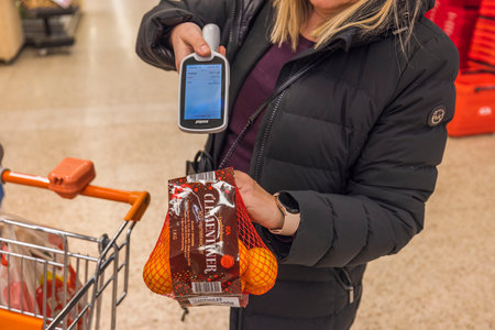 Close up view of woman scanning package of tangerines with scanner. Sweden. uppsala. 12.14.2022.のeditorial素材