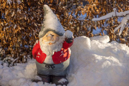 Beautiful view of figure of gnome standing in snow covered garden on sunny frosty winter day. Swedenの写真素材