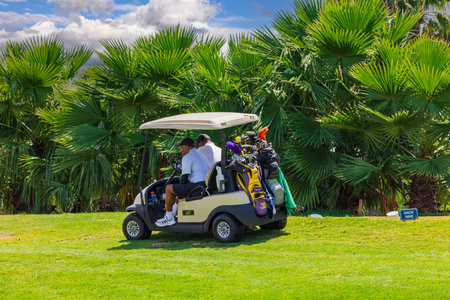 Beautiful view of two men playing golf and sitting in an electric golf cart. Aruba. 08/01/2023.のeditorial素材
