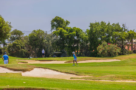 View of tourists playing golf on sunny summer day. Aruba. Oranjestad. 01.19.2023.のeditorial素材