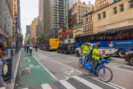 Cityscape view of one of Broadway streets. Heavy traffic of cars and cyclists between high...