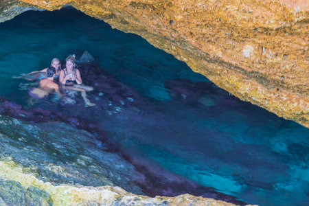 Beautiful view of group of young people swimming in gorge of rocks of Atlantic Ocean on island of Aruba. Aruba. Oranjestad. 02.11.2023.のeditorial素材