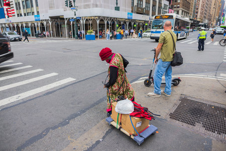 Close-up view of homeless woman with belongings on cart crossing street at crosswalk in Manhattan, New York. USA. 09.22.2022.のeditorial素材