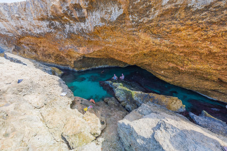 Beautiful view of group of young people swimming in gorge of rocks of Atlantic Ocean on island of Aruba. Aruba. Oranjestad. 04/03/2023.のeditorial素材