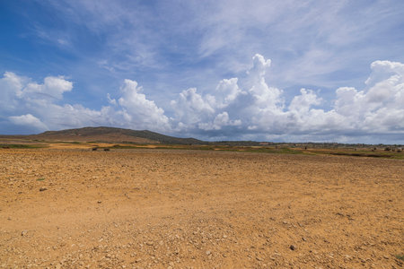Beautiful view of desert in northern part of island of Aruba against blue sky with white clouds.の写真素材