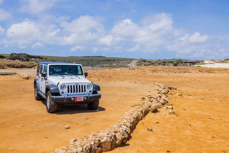 Beautiful view of off-road truck on desert landscape and pale blue sky with white clouds on background. Aruba. Oranjestad. 02/04/2023.のeditorial素材
