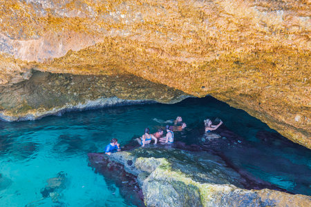 Beautiful view of group of young people swimming in gorge of Atlantic Ocean in natural pool. Aruba. Oranjestad.のeditorial素材