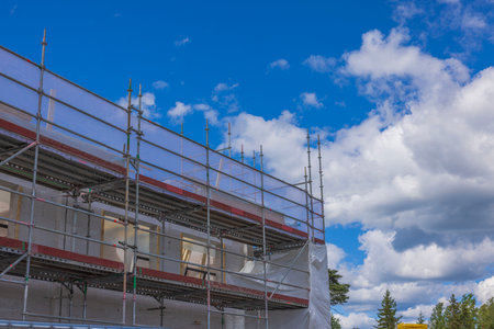 View of construction site fenced with scaffold with house under construction. Sweden.の写真素材