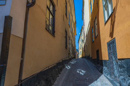 Beautiful view of narrow street between two yellow buildings with paving stone road. Sweden. Stockholm.の写真素材