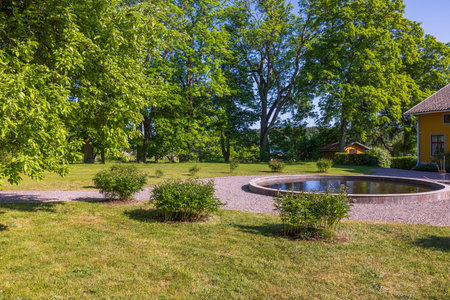 Beautiful view of garden landscape design with round decorative outdoor pond on green trees background. Sweden.の写真素材