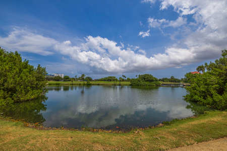 Beautiful view of lake and green golf courses on island of Aruba on blue sky with white clouds background.の写真素材