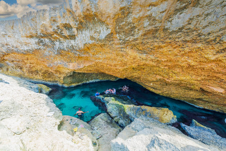 Beautiful view of group of people bathing in natural pool in gorge of rocks of Atlantic Ocean on island of Aruba. Oranjestad.のeditorial素材