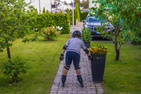 Close up view of young boy learning inline skating in garden on sunny summer day. Sweden.の写真素材
