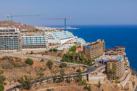 Beautiful top view of mountainous coast of Atlantic Ocean with moving cars on highway and hotels on mountain. Gran Canaria. Spain.の写真素材