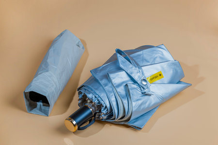 Close-up view of silver colored sun umbrella with uv protection spf 50+ isolated on beige background.の写真素材