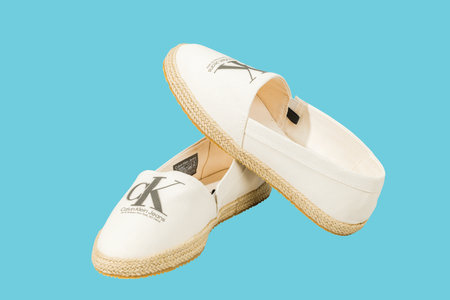 Close-up view of Calvin Klein espadrilles sandals isolated on blue background.のeditorial素材