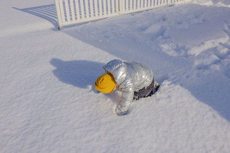 Close-up view of child playing in snow on backyard on bright winter day.の写真素材