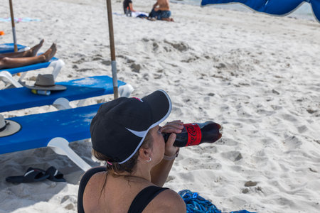Close-up view of woman drinking Coca-Cola zero on sand beach. USA. Miami Beach.のeditorial素材
