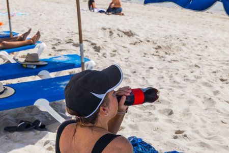 Close-up view of woman drinking soda from bottle on sand beach. USA. Miami Beach.の写真素材