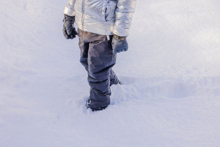 Close-up view of boy walking through snow on frosty winter day.の写真素材