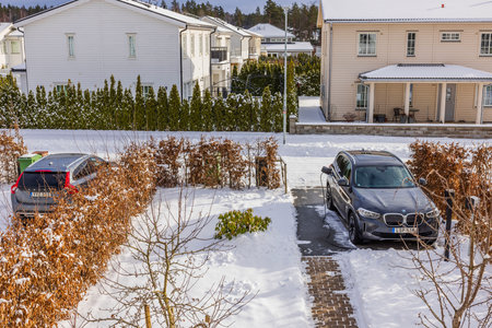 Beautiful winter view of modern village with cars parked in private parking lots in garden.のeditorial素材