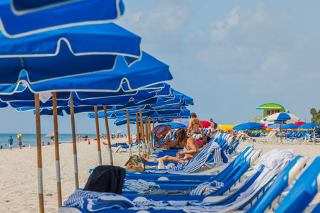 Close-up view of people on line of sun beds on sand beach. Miami Beach, Florida, USA.のeditorial素材