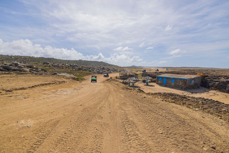View of tourists off-road cars on sandy desert road merging with pale blue sky on horizon.のeditorial素材