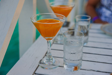 Close-up view of two glasses of alcoholic drink and glasses of water in restaurant on white table.の写真素材