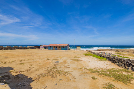Beautiful view of plot with house surrounded by stone fence in desert on Caribbean sea coast of island of Aruba.の写真素材