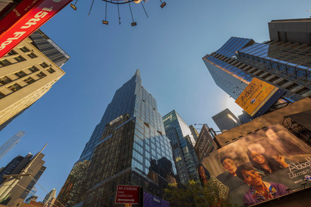 Skyscrapers of Manhattan ascend from bottom to top adorned with vibrant LED advertising panels against backdrop of clear blue sky. New York. USA.のeditorial素材