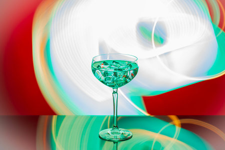 Close up view of martini glass with ice set against abstract green-white-red background.の写真素材