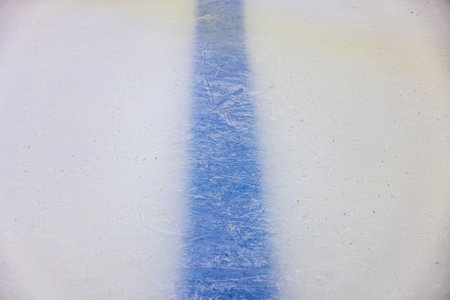 Close-up view of blue dividing line beneath intricately patterned surface of ice rink. Texture or background option.の写真素材