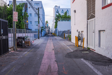 View of narrow street leading to Ocean Drive in Miami Beach with houses and parking along road. Florida.のeditorial素材