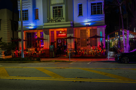 Colorful lights illuminate restaurant facade along Ocean Drive,  where diners on terrace enjoy meals. Miami Beach, USA.のeditorial素材