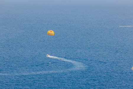 View of motorboat with yellow parachute above, capturing tourists enjoying parasailing water attraction in Atlantic Ocean. Gran Canaria. Spain.のeditorial素材