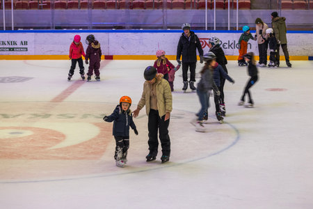 Children and adults skate on ice rink in sports complex.のeditorial素材