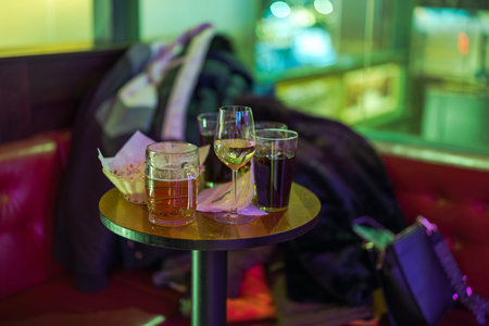 Close-up view of various drinks in glasses on a small bar table at a bowling center, with a blurred background.のeditorial素材