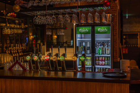 Close-up view of night bar with refrigerator for alcoholic beverages and beer taps dispensing various types of beer in bar.のeditorial素材