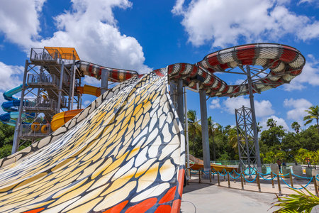 View of a beautiful water slide with a cobra-scale pattern on blue sky with puffy white clouds background.のeditorial素材