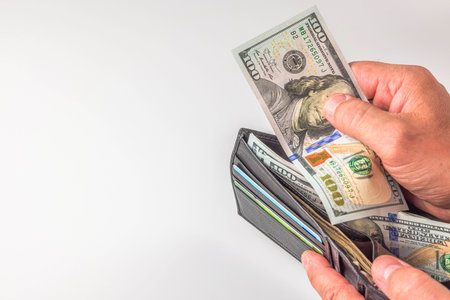 Close-up view of a person's hand retrieving dollar bills from a wallet.
