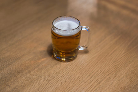 Close-up view of a beer mug filled with beer standing alone on a wooden table