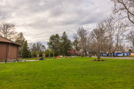 Beautiful view of a serene park in Paramus, New Jersey, featuring lush green lawns, benches, and a mural in the background under a cloudy sky. New Jersey. USA.のeditorial素材